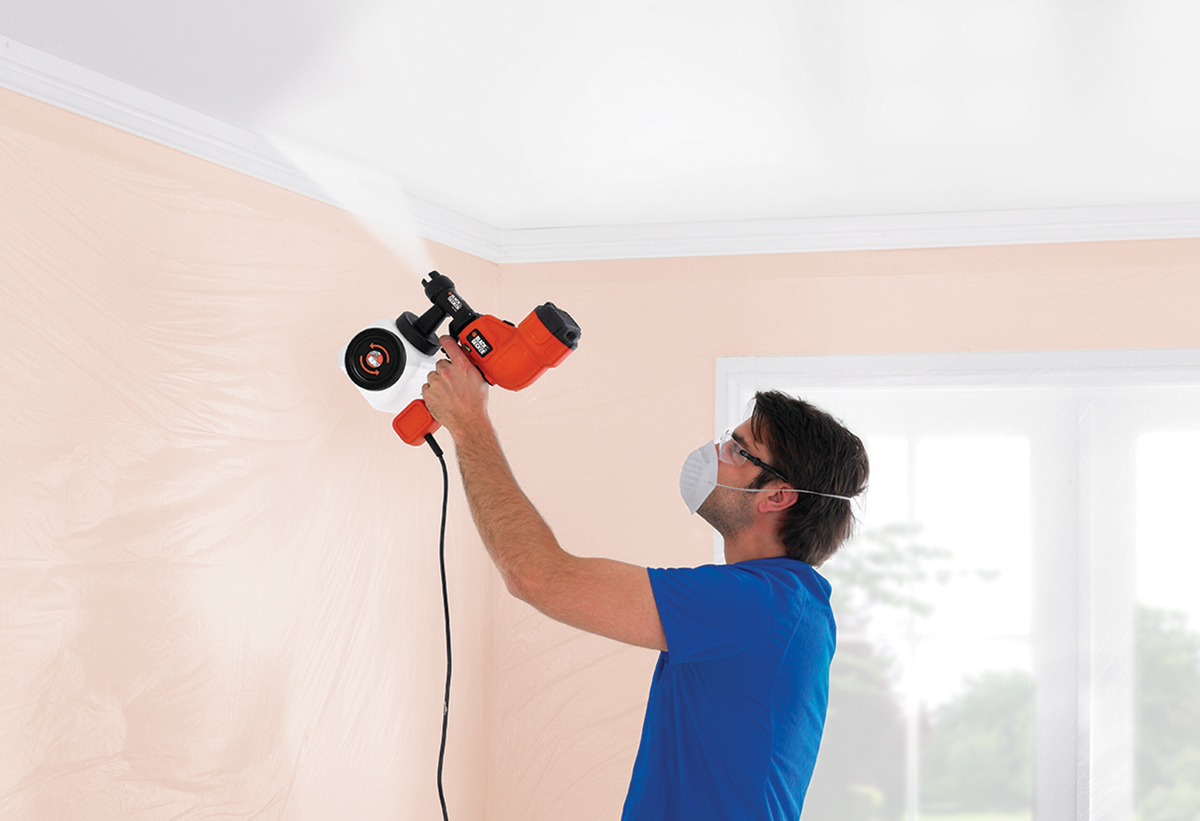 Απεικονίζεται ένας άνδρας να χρησιμοποιεί το πιστόλι βαφής για να βάψει το ταβάνι.